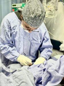 Pediatric healthcare professional performing a medical procedure in a pediatric intensive care unit (PICU).
