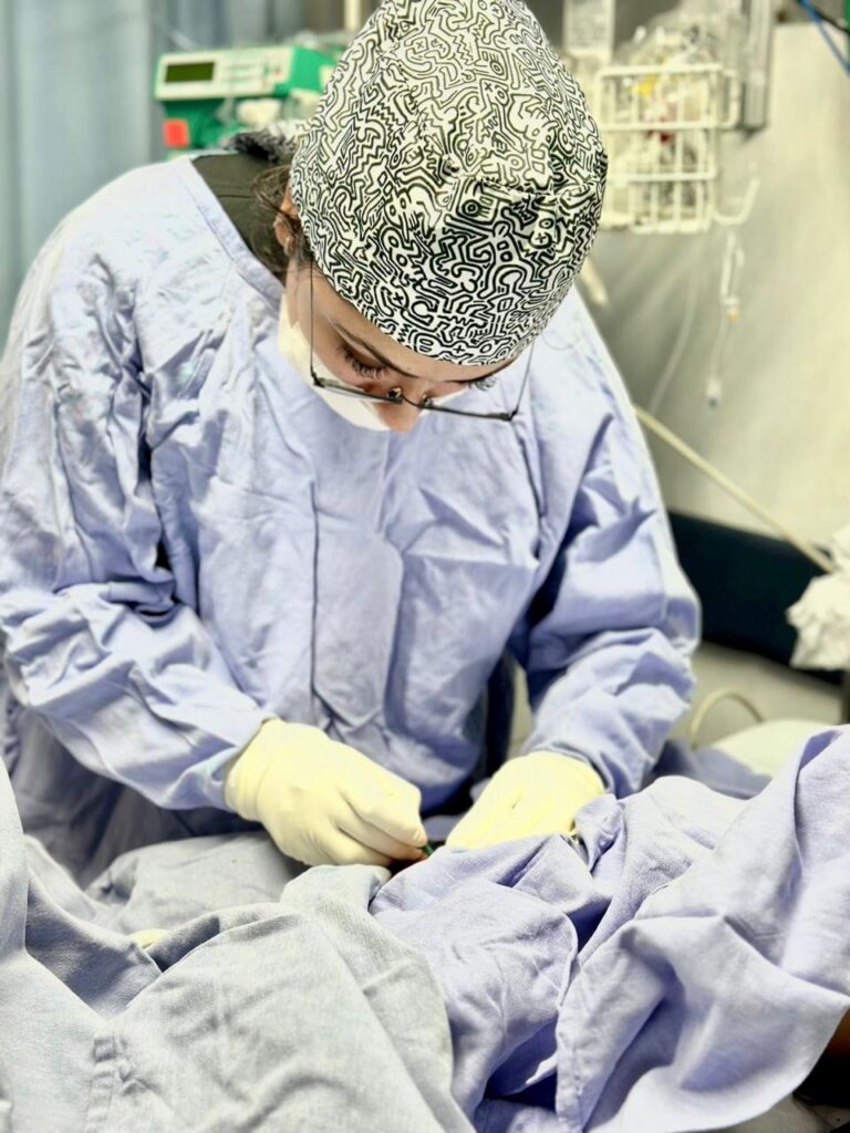 Pediatric healthcare professional performing a medical procedure in a pediatric intensive care unit (PICU).