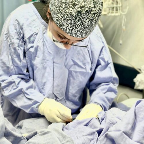 Pediatric healthcare professional performing a medical procedure in a pediatric intensive care unit (PICU).